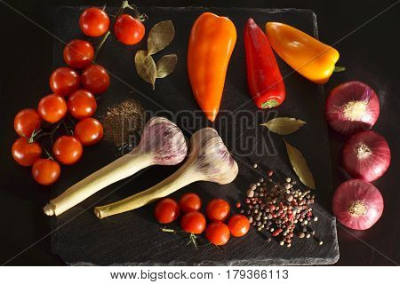 Vegetables and spices before cooking dinner on a dark background top view.