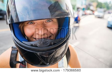 Beautiful happy girl in a black motorcycle helmet on the street. Close-up portrait.