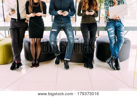Close Up Of Group Of Friends Standing On Table And Browsing In Their Divices In Modern Room