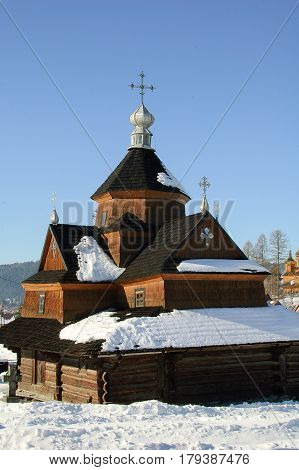Winter landscape with Little wooden village church against the sky. On the central dome stands the Christian cross