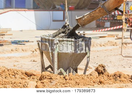 Concrete mixer truck pouring liquid concrete into the tower crane bucket at the construction site Close up