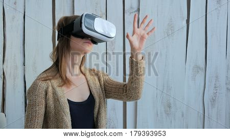 Young woman using Virtual Reality Glasses. Virtual reality mask. VR. White wooden background. Future and technology concept