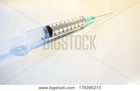 A medical syringe with a green tip is 8ml full of clear fluid against a white background