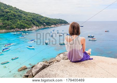 Young woman sitting on a cliff view tropical beautiful crystal clear sea at tropical island Similan Islands National Park Phang Nga Thailand