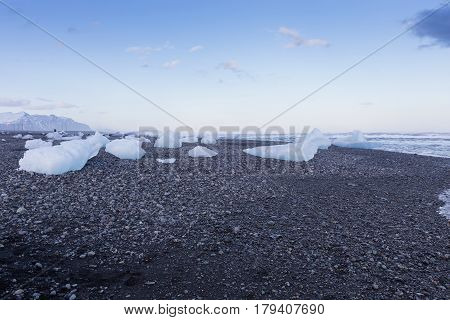 Ice breaking on rock sand beach Iceland natural winter season landscape background