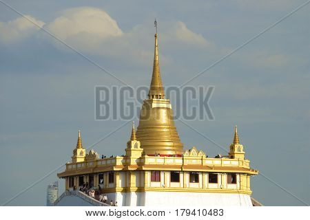 Chedi of the ancient Buddhist temple Wat Sacket (Temple of the Golden Mount) against the background of a cloudy sky. Bangkok, Thailand