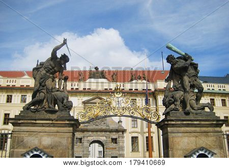 Prague Castle (Czech: Prazsky hrad) is castle complex in Prague, Czech Republic. Exit entrance arch with ancient statues architecture on empty summer blue sky background