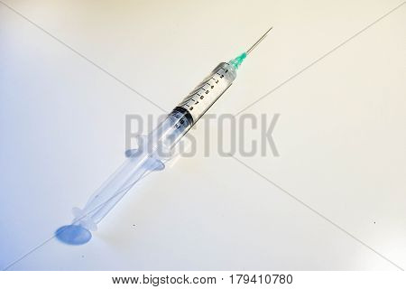 A medical syringe with a green tip is 8ml full of clear fluid against a white background