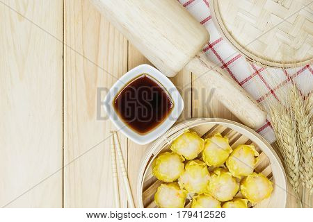 Steamed dumplings (chinese dim sum) in bamboo basket on wooden table background serve with chopsticks and napkin on a white background. Top view with copy space and text.