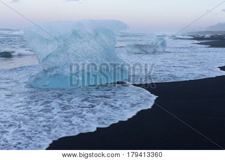 Ice breaking from glacier on black sand beach Iceland natural winter season landscape
