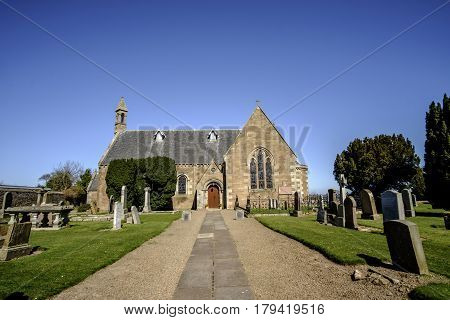 ATHELSTANEFORD EAST LOTHIAN SCOTLAND - 20 APRIL 2016 - Beautiful old stone church in the pretty village of Athelstaneford East Lothian Scotland against clear blue sky. Said to be the birthplace of Scotland's national flag St Andrew's Cross or Saltire.