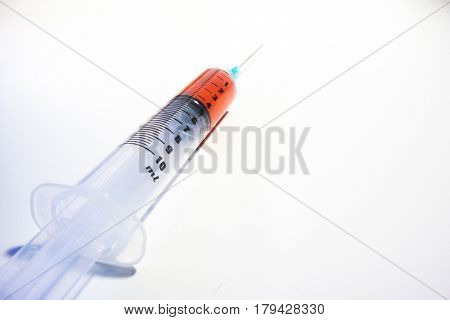 A green tipped syringe containing 4ml of red fluid (blood) from a low angle