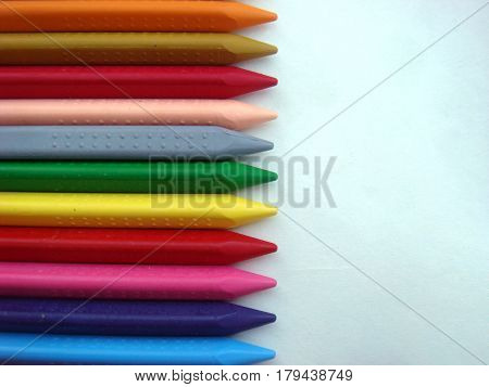 Multiple crayon color sticks on white paper