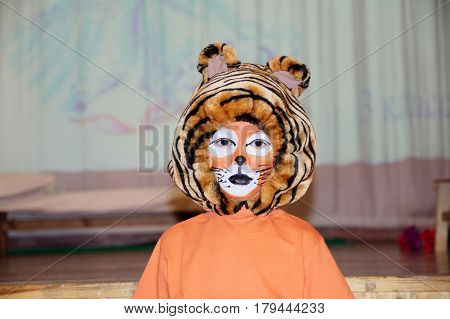 tiger costume for school performance. mask for child.Children face painting. Boy painted as tiger or ferocious lion. Boy actor playing role. theatrical tiger mask face. School activity