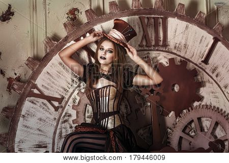 Portrait of a beautiful steampunk woman near big clock