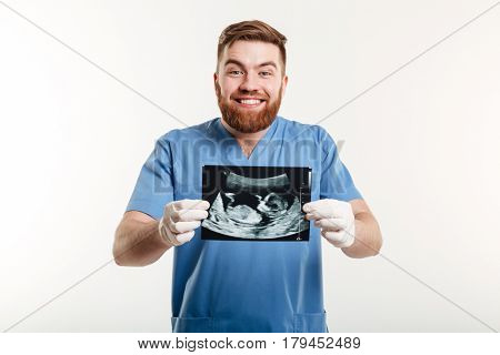 Portrait of a smiling excited male medical doctor or nurse showing radiograph x-ray image isolated on white background