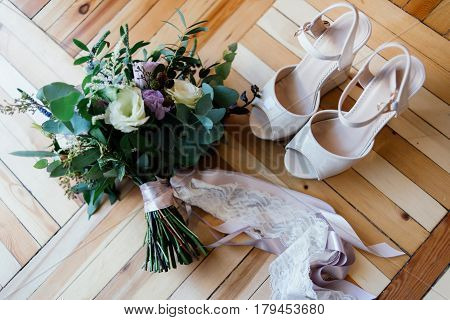 Bride's shoes and a bridal bouquet on the parquet