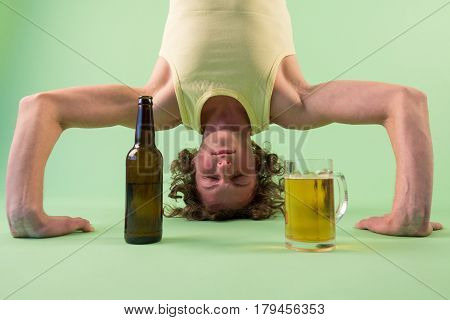 Caucasian man doing yoga with beer headstand pose