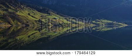 Shore of Lake Wagital. Green farmland mirroring in the water.