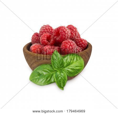 Raspberries in a wooden bowl isolated on white background. Raspberry with basil close-up. Vegetarian or healthy eating. Juicy and delicious raspberries