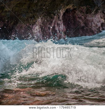 Ocean Waves Splach On The Background Of Rocks In The Bay. Turquoise Sea Water With White Foam Meet R