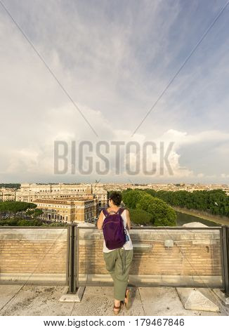 Female tourist wearing a backpack looks at the view of Rome on a summer's day.