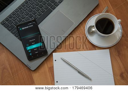 Nitra, Slovakia, march 28, 2017: Dolby Atmos application in a mobile phone screen. Workplace with a laptop, an earphones, notepad, pen and coffee on wooden background