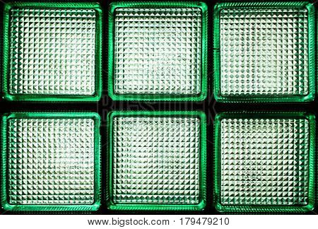 Six green transparent glass blocks. A fragment of a glass wall with daylight passing through it.