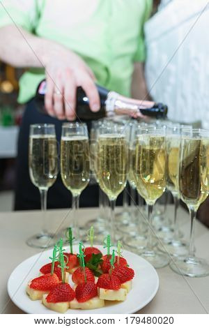 Strawberry fruit as a snack at the event. Snacks on a buffet table - fresh strawberries on pineapple. Catering snack during the event Champagne in glasses with a fruit snack.
