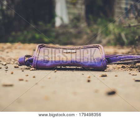 An old purple kids purse laying on the old abandoned ruined concrete sidewalk in an abandoned apartment complex