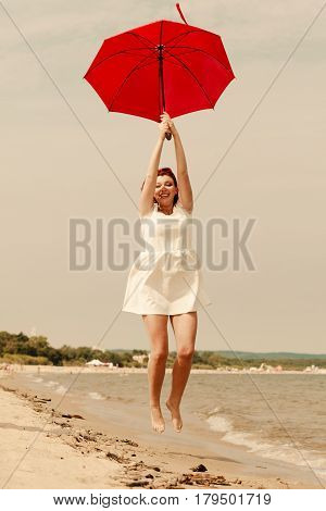 Redhead Woman Walking On Beach Jumping With Umbrella