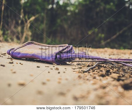 An old purple kids purse laying on a concrete sidewalk in an abandoned apartment complex