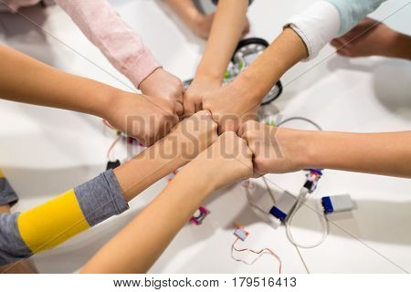 education, children, technology, science and people concept - group of happy kids with building kit making fist bump at robotics school