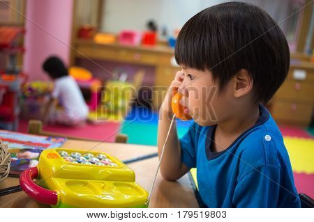 4 years old Asian boy playing pick up toy phone in toy room
