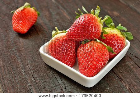 Strawberry fruit on wood background. Forest fruit in white idaeus. Delicious fresh berries.