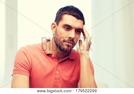 people, healthcare, stress and problem concept - unhappy man suffering from headache at home