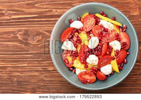 Tomato salad, mango and mozzarella with pomegranate seeds. Healthy low fat eating concept.