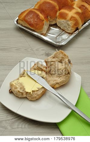 Hot cross buns butter knife and green napkin on a table