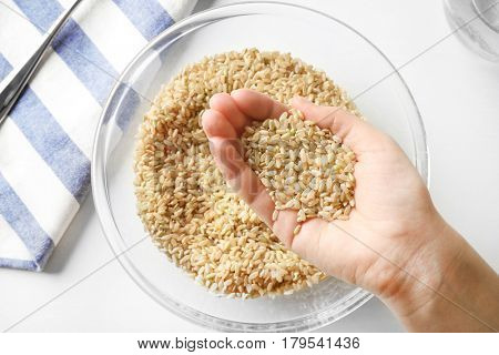 Handful of brown rice taken from glass bowl