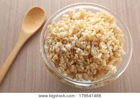 Glass bowl full of brown rice on wooden table