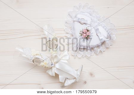 wedding rings on a pillow and two wedding glasses on a wood background
