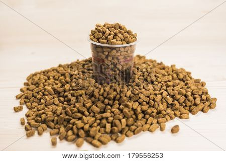 Dry pet nutrition with a cup in which the food is poured in the middle of the frame. Health pet concept