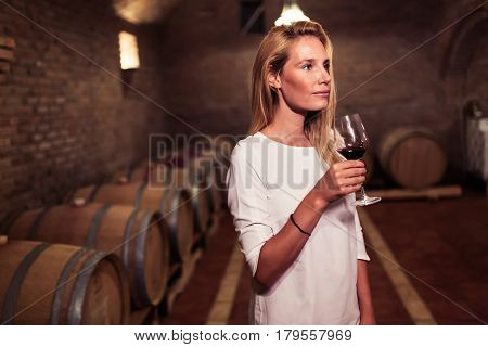 Beautiful woman oenologist tasting wine in winegrower cellar