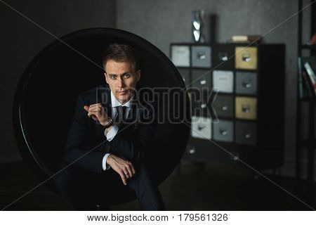 young businessman sitting in chair on grey background