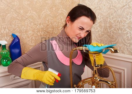 Young woman in rubber gloves cleans bathroom