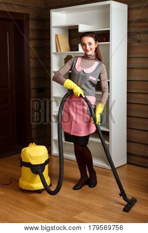 Woman in uniform and gloves with vacuum cleaner