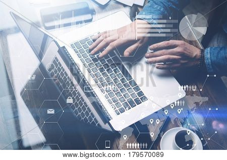 Concept of cyber security.Man working at sunny office on laptop while sitting at the wooden table.Background of digital screen, virtual worldwide connection icon, diagram, graph interfaces.Blurred