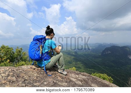 successful woman hiker taking photo with cellphone hiking on mountain peak