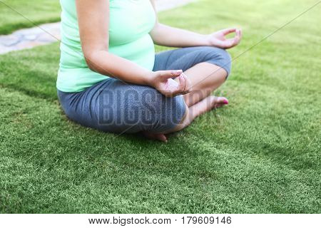Beautiful pregnant woman meditaiting in summer park. Pregnant yoga