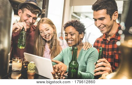 Multiracial friends drinking beer and having fun with tablet at cocktail restaurant - Friendship concept with young people enjoying time together - Warm retro filter with focus on afroamerican woman